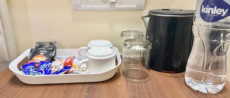A kitchen counter with a tray of snacks, a kettle, a water bottle, and a coffee maker.
