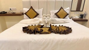 Cama bem arrumada com arranjo decorativo de toalhas, destacando uma toalha em formato de coruja.