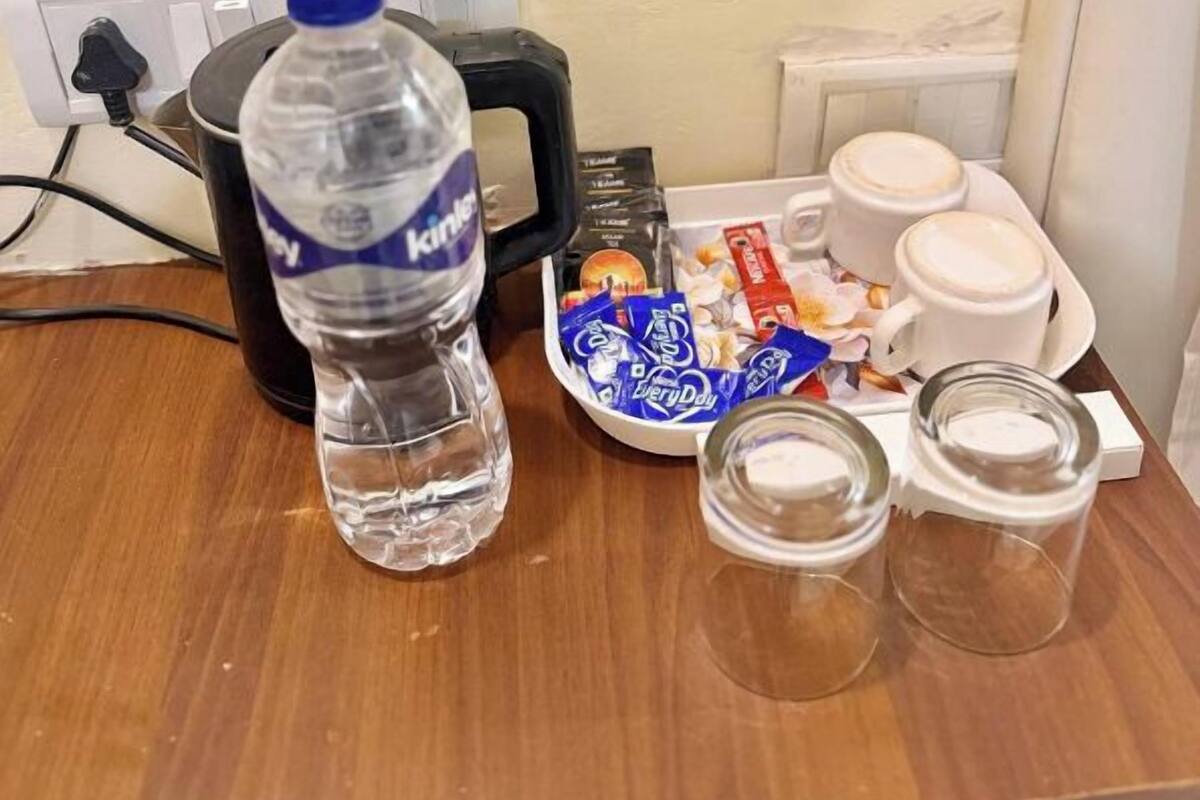 Une chambre d’hôtel équipée d’une bouteille d’eau, d’un plateau avec des en-cas, d’une machine à café et de verres.