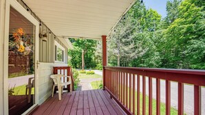 A wooden deck with a red railing, a bench, and a chair. - Cornerstone Escape - Robin Vacation Rentals (Benton)