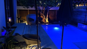 An outdoor patio area with a pool, seating, and a covered section.