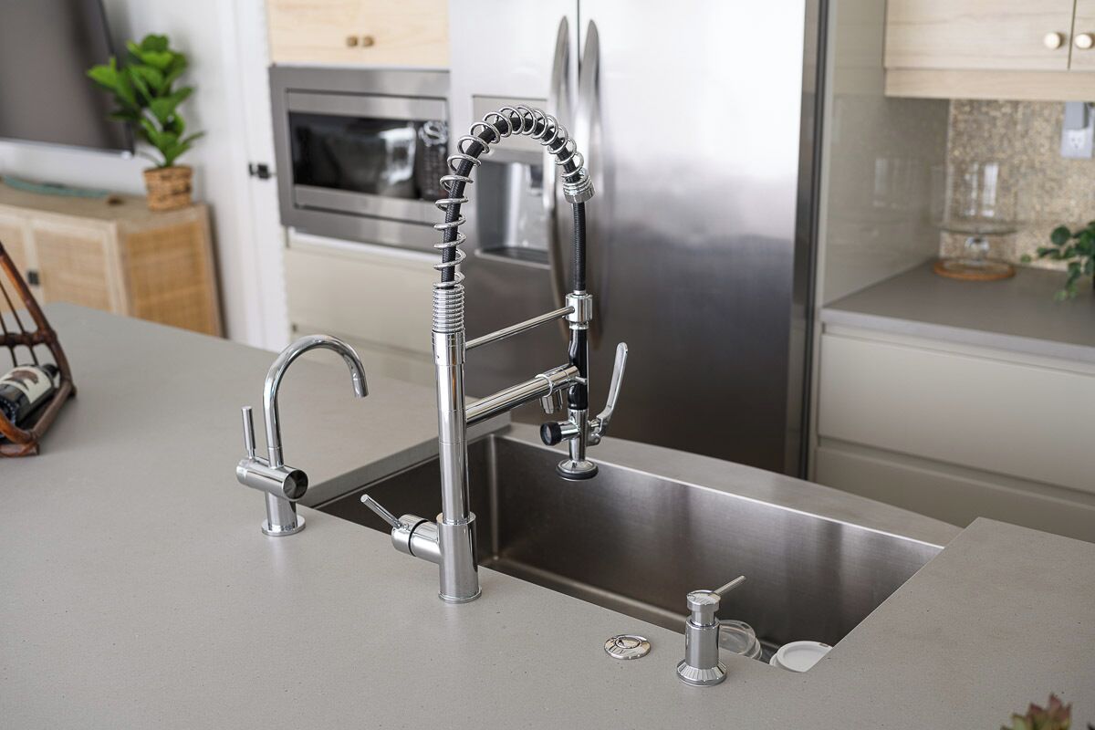 A modern kitchen with a stainless steel sink, a double faucet, and a built-in oven.
