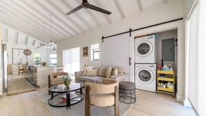 A spacious living room with a sofa, chairs, a coffee table, and a washing machine.