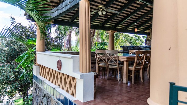 An outdoor patio area with a wooden table and chairs, a ceiling fan, and a tiled floor. - Anana Rancho San Rafael Master BD Lake Views (Chapala)
