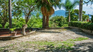 A paved courtyard with a stone statue, palm trees, and a view of a mountain range. - Anana Rancho San Rafael Master BD Lake Views (Chapala)