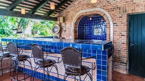 A bar area with a tiled counter, metal chairs, and a brick wall with a blue-tiled archway. - Anana Rancho San Rafael Master BD Lake Views (Chapala)
