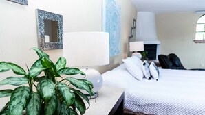 A hotel room with a bed, two bedside lamps, a potted plant, a mirror, and a wall with a decorative piece. - Anana Rancho San Rafael Master BD Lake Views (Chapala)