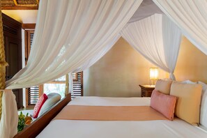 A bedroom with a canopy bed, wooden headboard, bedside table with lamp, and a window with blinds. - Anana Hacienda Chekul Sanctuary w Private Beach (Tulum)