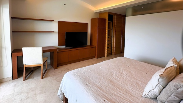 A modern bedroom with a bed, a desk, a television, and a wardrobe. - Anana El Dorado 305 Condo With Pool Lake Views (Chapala)