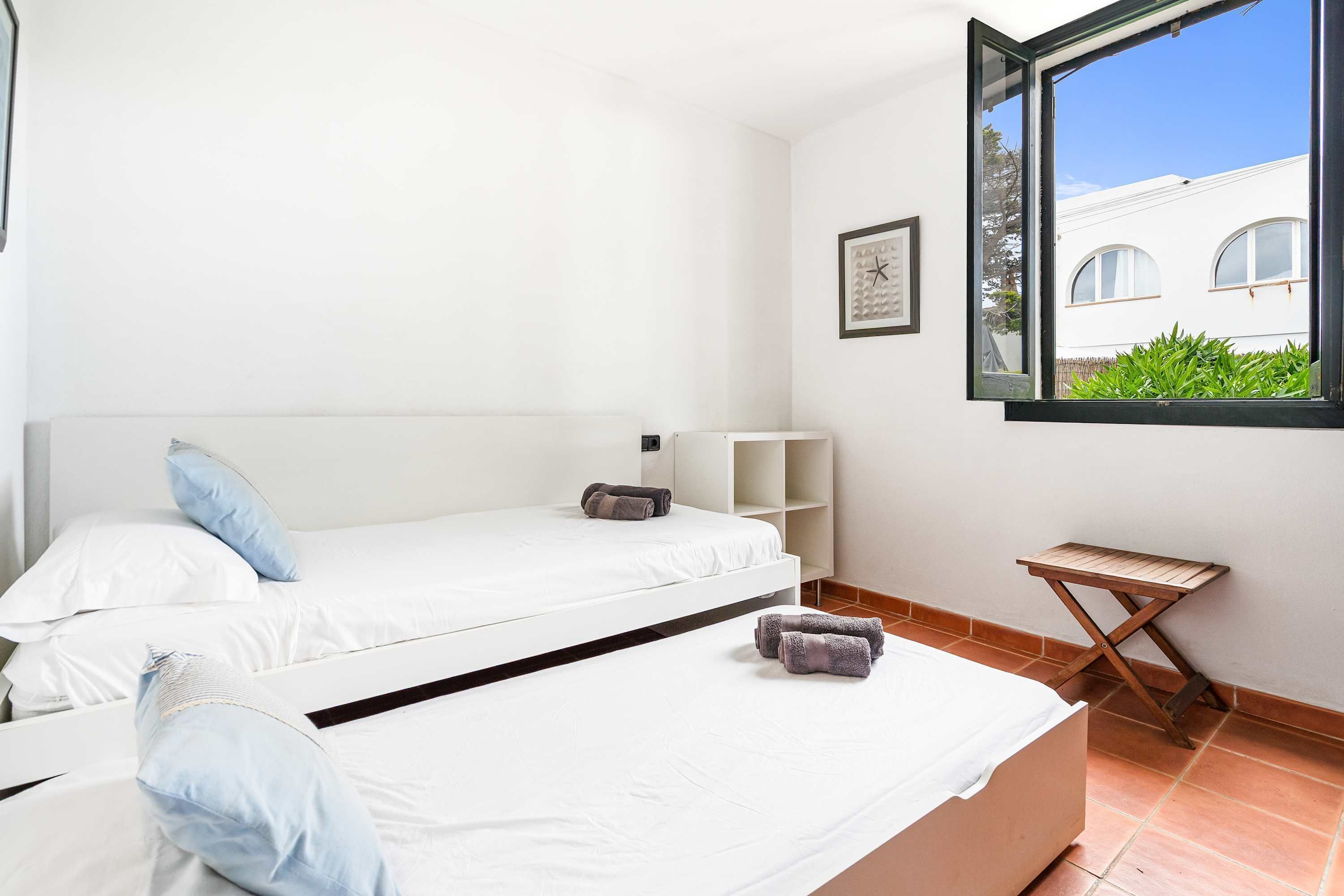 Ein Zimmer mit zwei Betten, einem Fenster und einem kleinen Tisch.