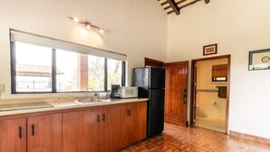 Eine Küche mit Holzschränken, einem schwarzen Kühlschrank, einer Mikrowelle und einem Spülbecken.