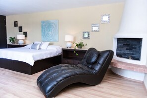 A modern bedroom with a bed, a chaise lounge, a fireplace, and wall art. - Anana Rancho San Rafael Villa With Pool Views (Chapala)
