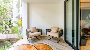 Ein modernes Interieur mit zwei grünen Sesseln, einem Holztisch und einer Glastür, die in einen Garten führt.