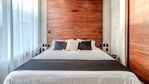A modern hotel room with a wooden ceiling, a large bed with white and dark bedding, and a nightstand with a lamp. - Anana Casa Karmond Luxury Villa With Pool (Tulum)
