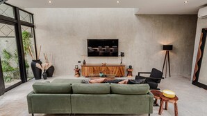 A modern living room with a green sofa, wooden sideboard, and a flat-screen TV mounted on the wall. - Anana Casa Karmond Luxury Villa With Pool (Tulum)