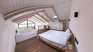 Un dormitorio con piso de madera, una cama, un ventanal y un baño con bañera.