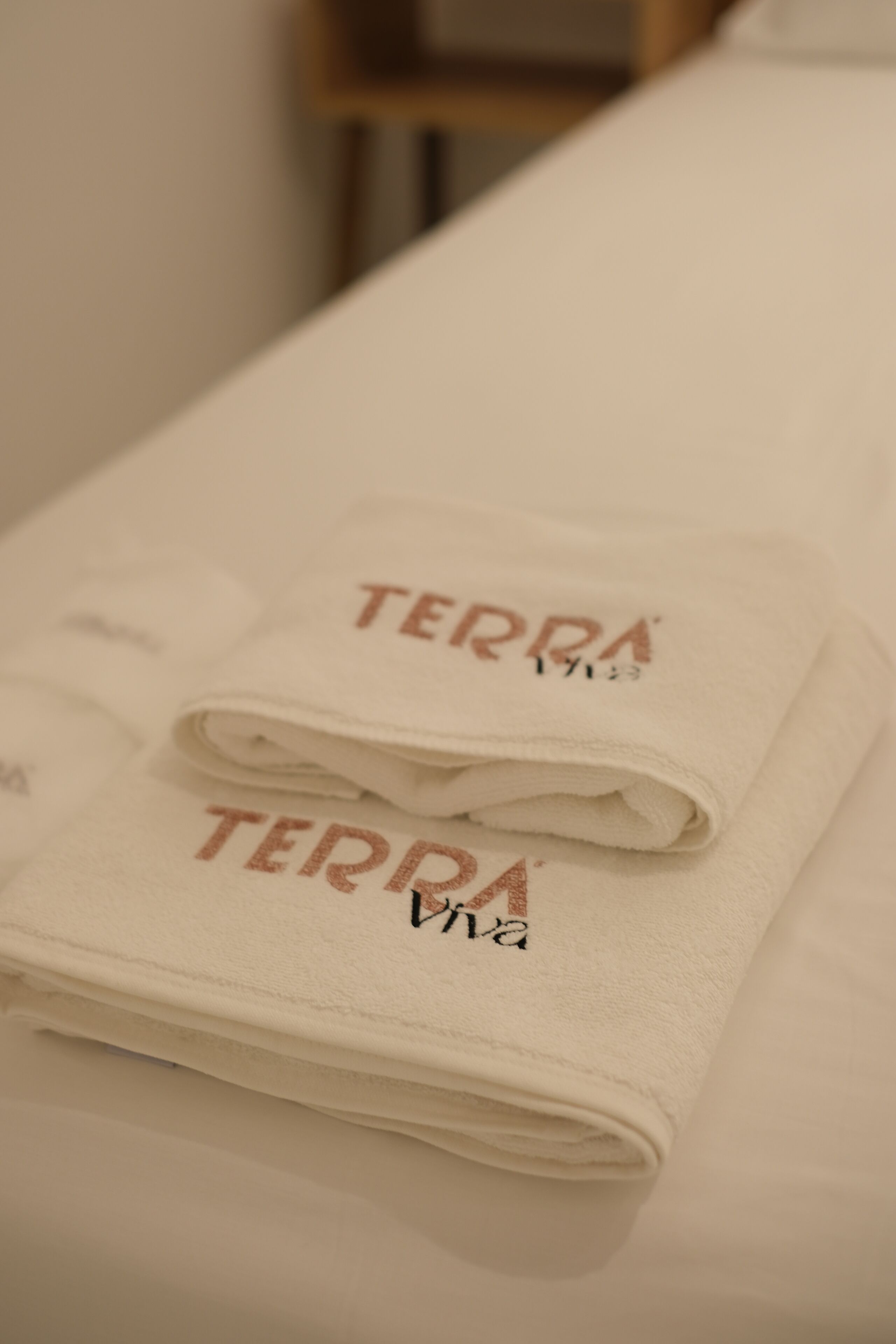 Una toalla blanca doblada con la palabra "TERRA" impresa, sobre una cama.
