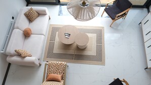Una sala moderna con sofá blanco, sillón estampado y una mesa de centro redonda.