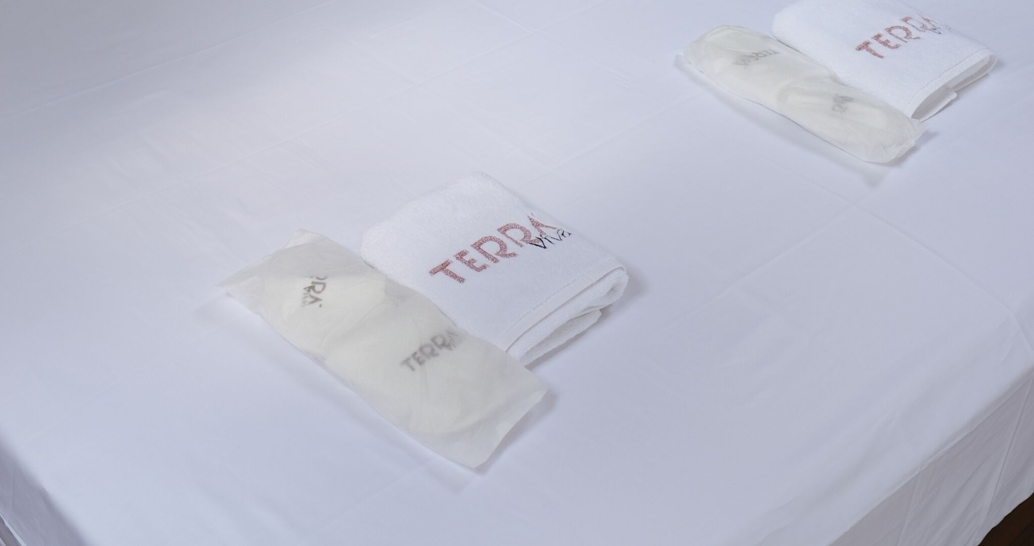 A white table with three folded towels labeled "TERRA" and "Viva".