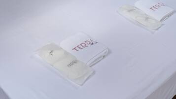 A white table with three folded towels labeled "TERRA" and "Viva".
