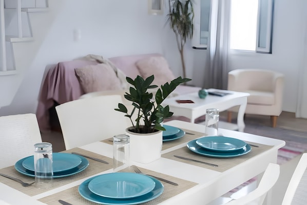 A dining table set with blue plates, a potted plant, and a white chair.