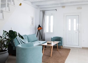 A modern living room with a sofa, two armchairs, a coffee table, a floor lamp, and a potted plant.