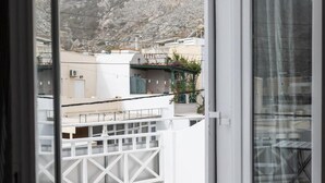 Una porta aperta su un balcone con vista su edifici e montagne.