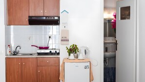 A compact kitchen with wooden cabinets, a gas stove, a sink, and a small refrigerator.