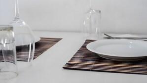 A dining table with a white plate, clear glassware, and a bamboo placemat.
