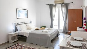 A bedroom with a bed, bedside table, lamp, and a view of the outside.