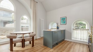 A kitchen with a round table, grey cabinets, and large windows.