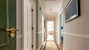 A hallway with a wooden floor, white walls, and a green door.