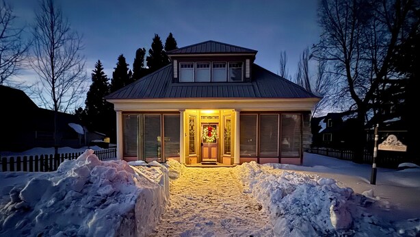 A two-story house with a covered porch and a front door decorated with a wreath.
