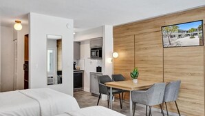 Ein modernes Hotelzimmer mit Essbereich, Küchenzeile und einem großen Fenster mit Außenblick.