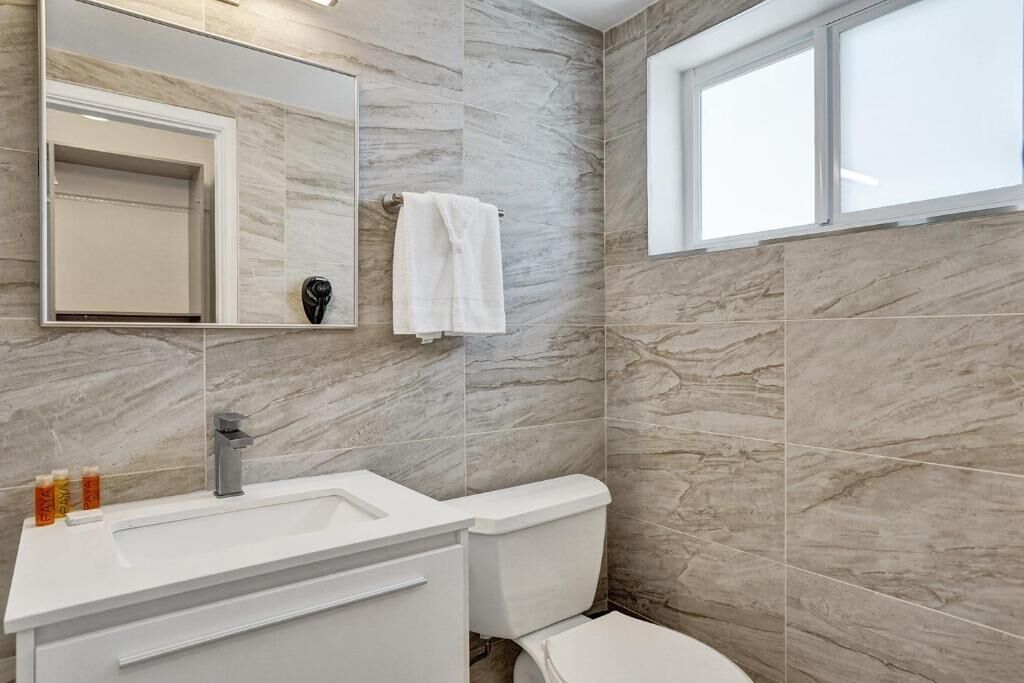 Un bany amb un lavabo blanc, un vàter i un mirall gran.