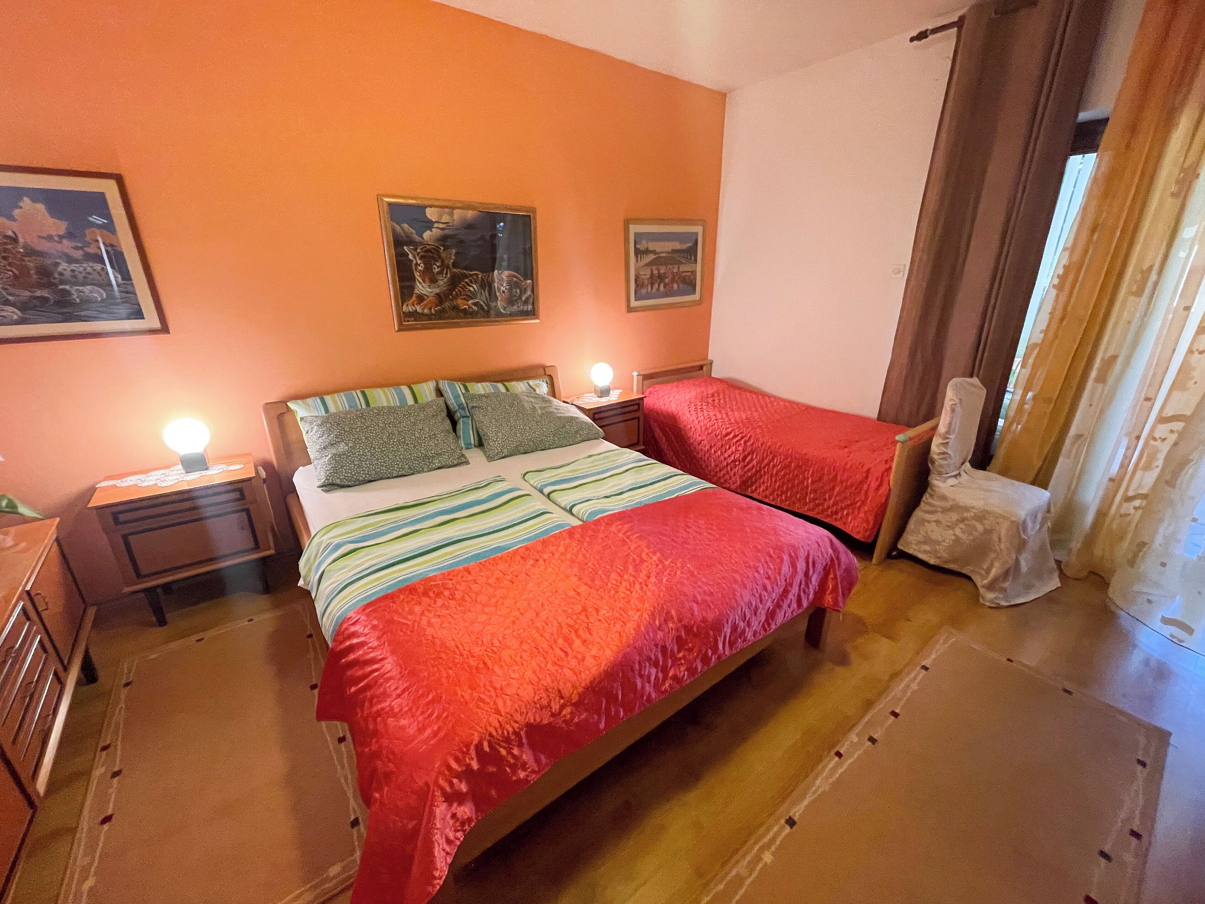 A bedroom with a large bed, two bedside tables, a chair, and two wall-mounted lamps.