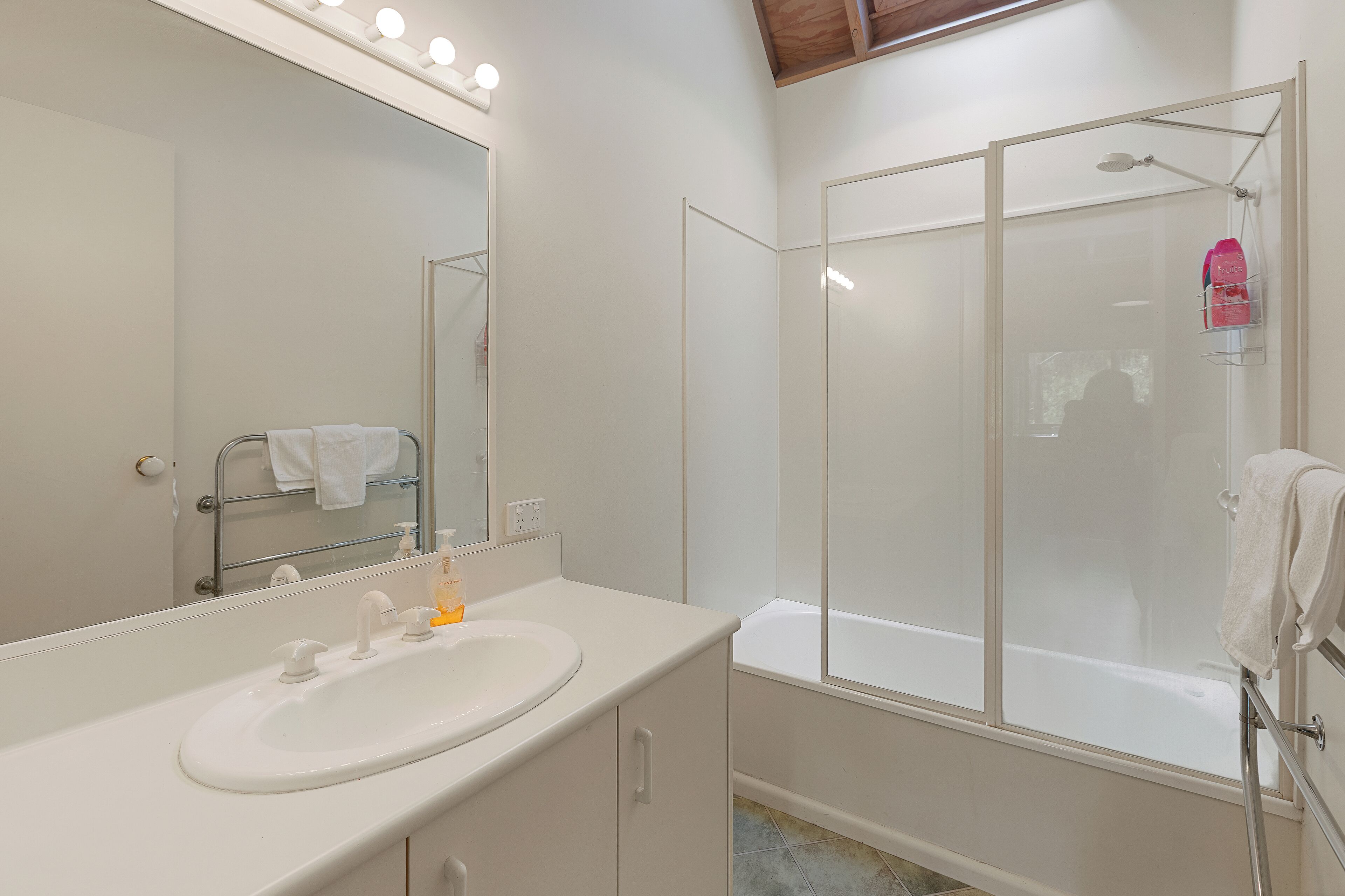Une salle de bain avec un lavabo blanc, un miroir et une douche à parois de verre.