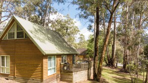 A wooden cabin with a balcony, surrounded by trees.