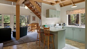 A spacious kitchen with a central island, wooden chairs, and a view of the outdoors.