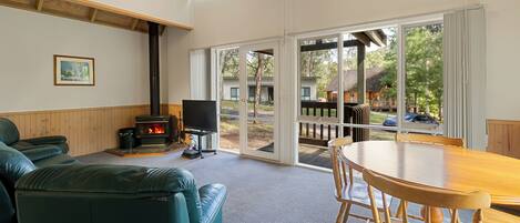 A cozy living room with a fireplace, a television, and a dining area with a wooden table and chairs.