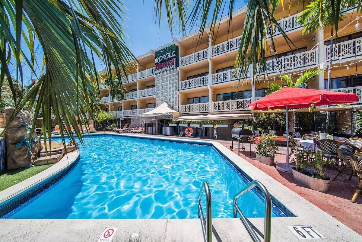 A hotel with a swimming pool, outdoor seating, and a sign reading "Royal Hotel."