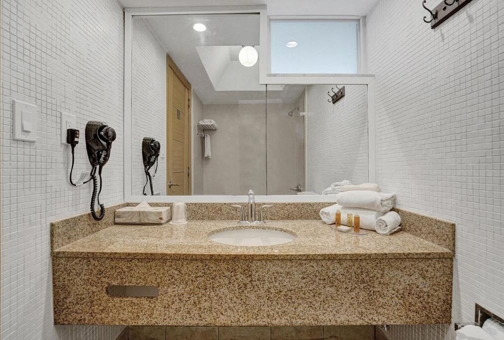 Un baño moderno con encimera de granito, un lavabo y un espejo grande.