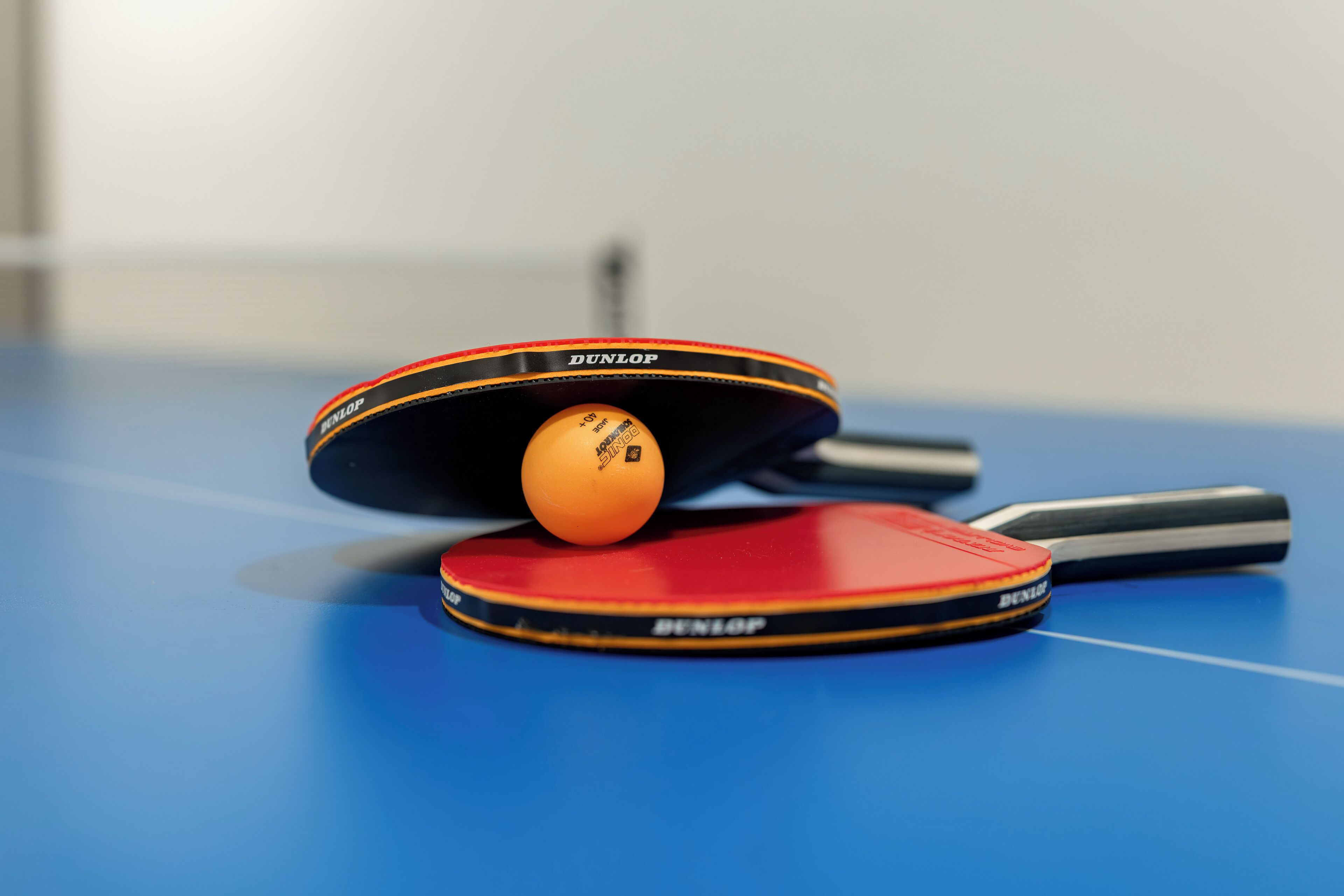 Two ping pong tables with a ball on one of them.