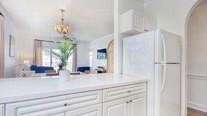 A modern kitchen with white cabinetry, a white refrigerator, and a central island with a plant.