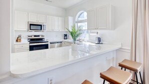 A modern kitchen with white cabinetry, a central island, and bar stools.