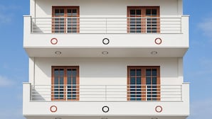A modern multi-story building with a white facade, multiple balconies, and a blue gate at the entrance. - Let'stay- Noida (Noida)