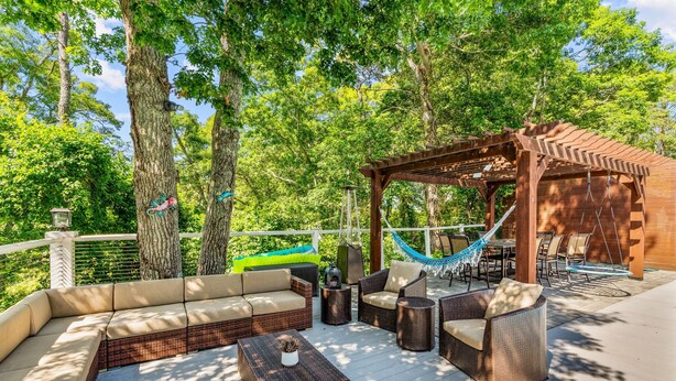 An outdoor patio with wicker furniture, a hammock, and a pergola. - Barnstable Cape Cod Retreat | Pool, Fire Pit & BeachSticker (Barnstable)
