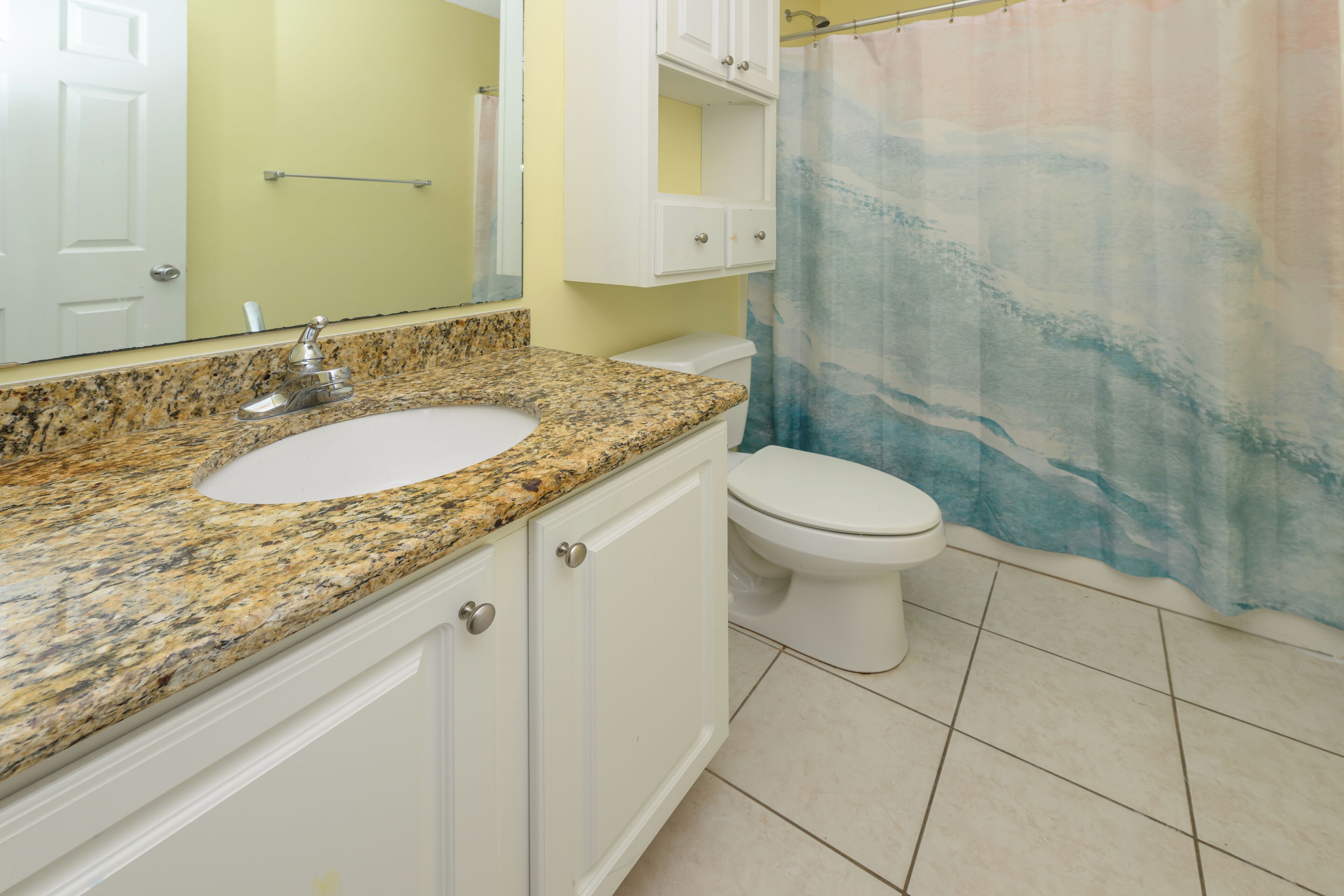Une salle de bain avec un lavabo en granit, des toilettes et un rideau de douche.