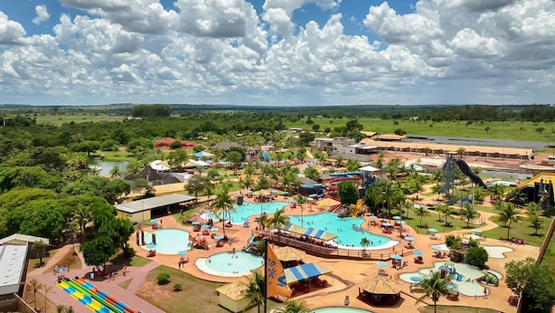 A theme park with multiple water slides, pools, and a large open area with palm trees.