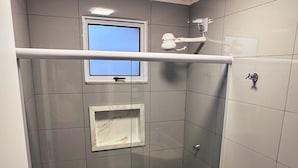 A modern bathroom with a glass-enclosed shower, a toilet, and a sink.